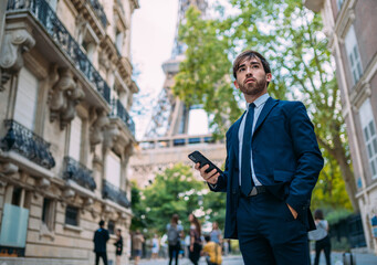 Holidays in Paris. Man in a suit using her smartphone in Paris, France. European worker. Street...