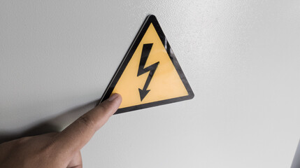 The male hand is pointing at the warning symbol image there is an electric voltage.
