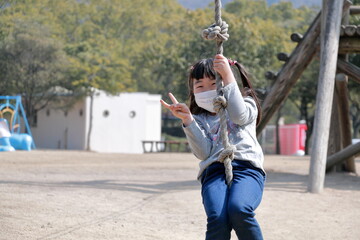 	公園の遊具で遊ぶマスク姿な女の子