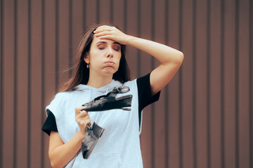 Unhappy Girl Holding a Broken Shoe that needs Repairing . Disappointed woman trying to find a...
