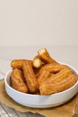 close up of churros with sugar in white bowl, top view