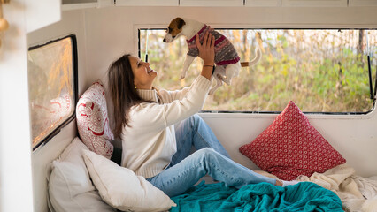 Caucasian woman sitting in a van hugging with dog Jack Russell Terrier. Travel in a camper in the...
