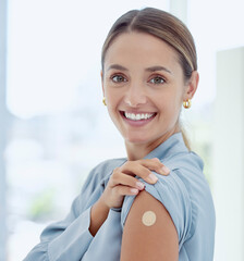 Portrait of woman with a plaster on her arm from vaccine or an injection. Young, smiling woman with...