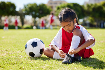 Soccer, sports and girl tie her shoes in training practice for fitness, wellness and youth...