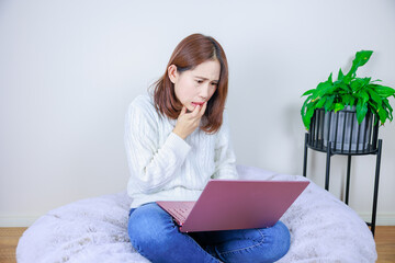 ノートパソコンを開いて悩む女性