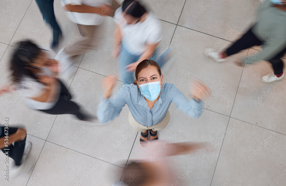 Wall mural Angry business woman with a mask for covid and people walking around her. Young girl wearing face mask in a crowd, frustrated and shaking her fist. Aerial view of upset female in mall or office