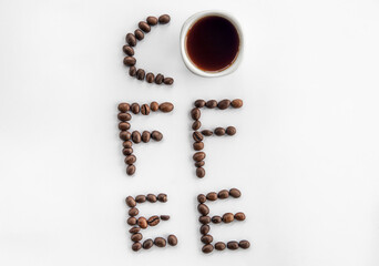 Cup of coffee and coffee beans make the word coffee, flat lay.