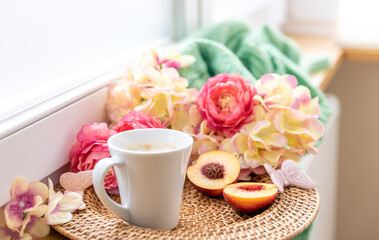 Home composition with a cup of coffee, flowers and a knitted element.