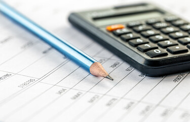 Calculator and pencil close-up on a blurred background.