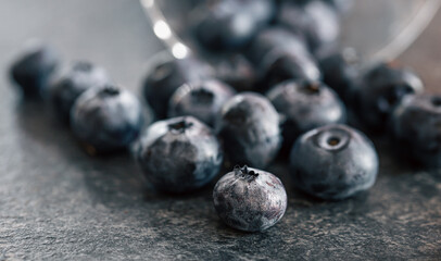 Macro photography, blueberries scattered on a dark surface.