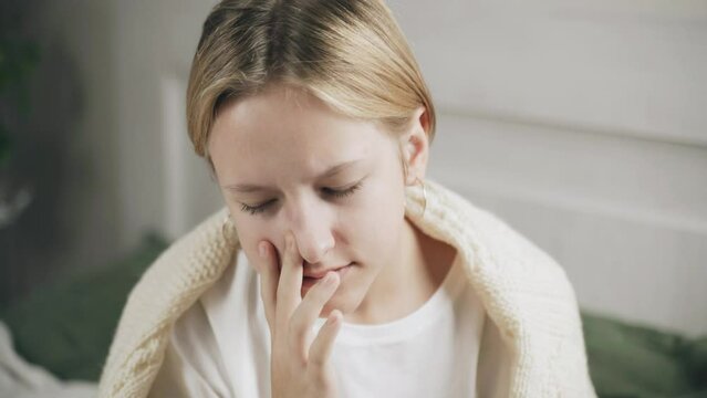 An unhealthy girl with a stuffy nose uses a nasal spray to treat a cold. Medication for nasal congestion and allergies