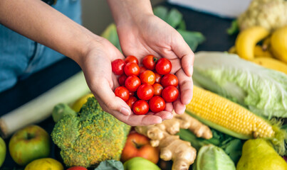 Small cherry tomatoes in women's hands on a blurred background.