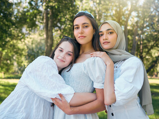 Group of women hug, show diversity, support and solidarity together, against forrest or garden background. Multicultural friends stand in unity, in outdoor portrait with trees or woods in backdrop