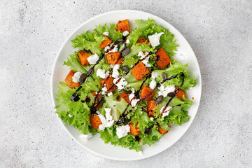 Pumpkin salad with green lettuce, feta cheese. Autumn healthy salad with roasted baked pumpkin on...