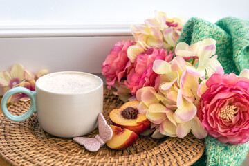 Home composition with a cup of coffee, flowers and a knitted element.