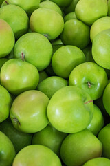 Green apple texture, lots of green apples. Apples storage. Bunch of green delicious apples in a box in supermarket