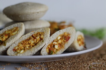 Paneer stuffed kodo millet Idly. Steamed savory cakes made of kodo millets and lentil flour stuffed with a patty made of scrambled cottage cheese with onions and tomatos