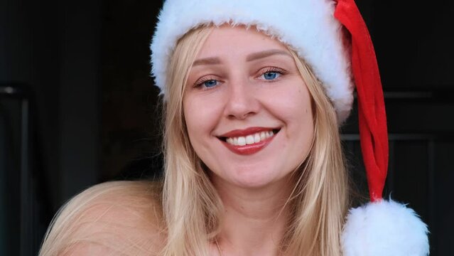 Happy woman celebrating Christmas wearing Santa hat dancing with shoulders and smiling. Christmas time. Positive smiling caucasian female middle age looking at camera. Christmas holiday, winter. Chris