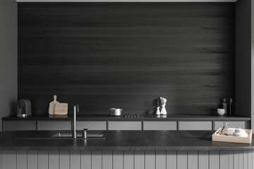 Black kitchen interior with countertop, sink and kitchenware. Empty wall