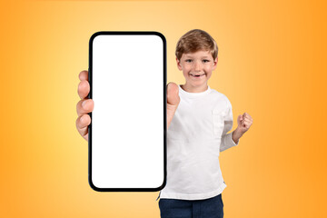 Happy boy with a fist, large phone mockup display on grey backgr