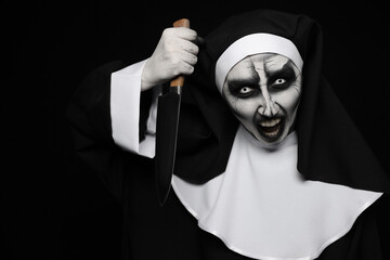Scary devilish nun with knife on black background. Halloween party look