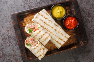 Shawarma sandwich gyro fresh roll of lavash closeup on the wooden board on the table. Horizontal...