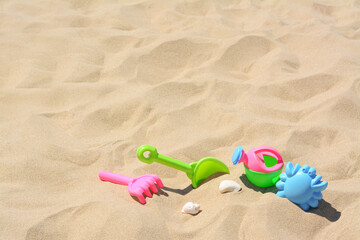 Bright plastic rake and shovel on sand. Beach toys. Space for text