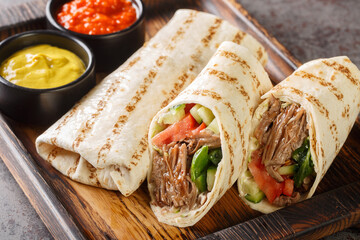Doner kebab or shawarma with beef and fresh vegetables closeup on the wooden board on the table. Horizontal