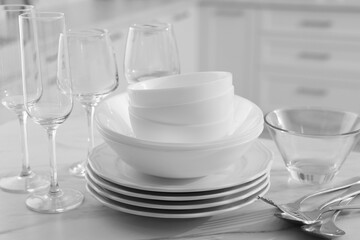Fototapeta na wymiar Different clean dishware, cutlery and glasses on white marble table in kitchen, closeup
