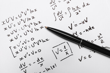 Sheet of paper with mathematical formulas and pen, top view