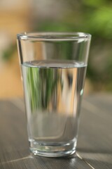 Glass of pure water on wooden table against blurred background, closeup