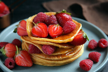 Tasty pancakes with fresh berries and honey on plate, closeup