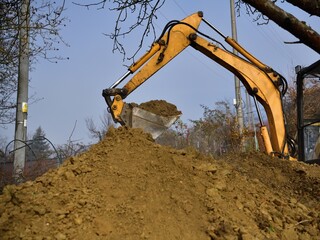 A road excavator dredges the hole near the family house 