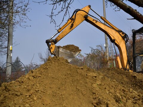 A road excavator dredges the hole near the family house 