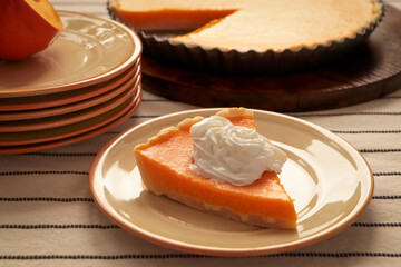 Piece of fresh homemade pumpkin pie with whipped cream on table