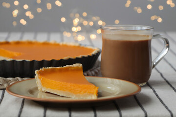 Piece of fresh homemade pumpkin pie served with cocoa on table