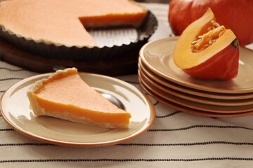 Plate with piece of homemade pie and fresh pumpkin on table