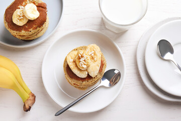 Banana pancakes served on white wooden table, flat lay