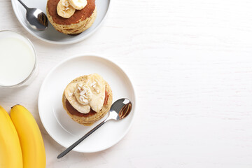Banana pancakes served on white wooden table, flat lay. Space for text