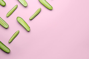 Cut fresh ripe cucumbers on light pink background, flat lay. Space for text