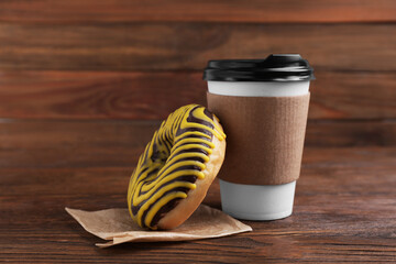 Tasty frosted donut and hot drink on wooden table
