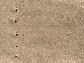 five cigarette butts arranged as bullet points in sand on beach