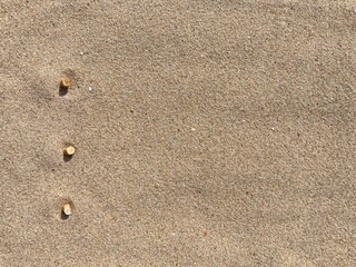 Fototapeta na wymiar three cigarette butts arranged as bullet points in sand on beach