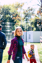 cute teenage girl with blond hair with her brother in the park in autumn on a sunny day selective focus