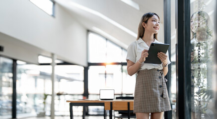 Elegant businesswoman standing in office with digital tablet