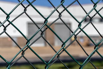 View through chain link fencing to defocussed factory building