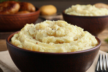 Bowl of tasty mashed potatoes with black pepper on table, closeup