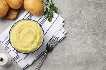 Bowl of tasty mashed potatoes served on grey marble table, flat lay. Space for text