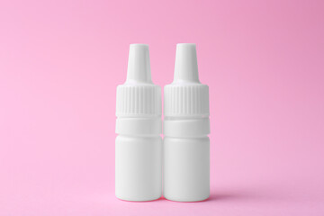 Bottles of medical drops on pink background