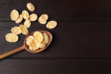Spoon and tasty crispy corn flakes on wooden table, flat lay. Space for text
